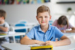 © Halfpoint - A small school boy sitting at the desk in classroom on the lesson, looking at camera.