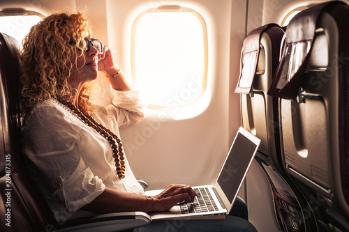 Fotografía Business adult curly blonde woman travel on airplane connected to internet with