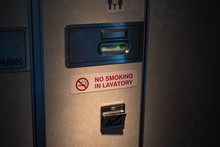 Door of Vacant lavatory in airplane with No smoking sign, close up.