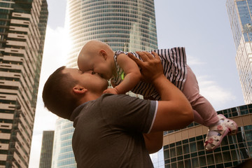 Father and one year old daughter against the sky and skyscrapers. Travel with children, the development of emotional intelligence. Early development.