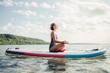 © anoushkatoronto - Middle age Caucasian woman practising yoga on paddle sup surfboard at sunset. Female stretching doing workout on lake water. Modern individual hipster outdoor summer sport activity.