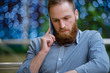 © ruslanshug - serious handsome bearded young caucasian man in shirt calling holding cell phone standing indoors with background with blue bokeh