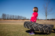 © Cavan Images - A strong little girl struggles to hold up a large tire in a park
