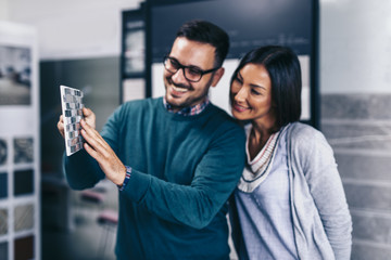 Middle age man choosing ceramic tiles and utensils for his home bathroom and female seller helps him to make right decision