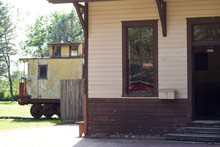 Exterior View Of A Old Rural Railway Train Station With A Caboose In The Background