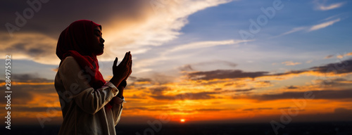 Fotografía Silhoueitte of young muslim woman pray with beautiful sunset/ sunrise in backgro