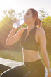 © fotofabrika - Young beautiful woman drinking water during morning jogging in the park