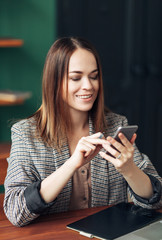 young beautiful girl looking at the phone screen and smiling