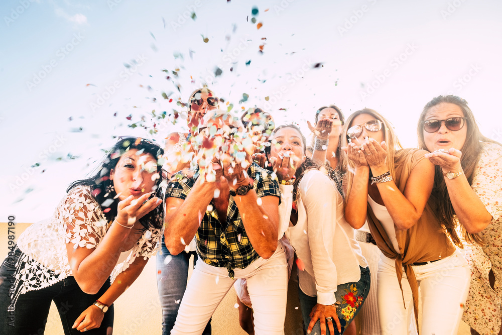 Happiness and joyful concept - group of happy women people celebrate. all together blowing confetti and having fun - new year eve and party event for group of beautiful girls -white clear  background - obrazy, fototapety, plakaty 