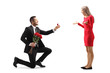 Young man kneeling with roses and an engagement ring and proposing to a surprised young woman