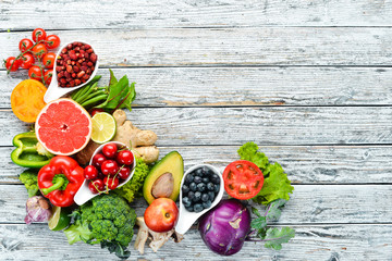 Fresh fruits and vegetables on a white wooden background. Top view. Free space for your text.