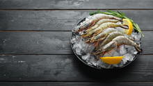 Black Tiger Prawns With Lemon On Ice. Seafood. Top View. On A Black Background. Free Copy Space.