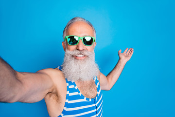 Sticker - Close up photo of retired man in eyeglasses eyewear holding his palm making selfie wearing striped swim wear isolated over blue background