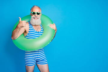 Wall Mural - Portrait of cheerful grandfather in eyewear eyeglasses showing approval sign wearing striped bathing suit isolated over blue background