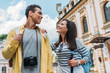 © LIGHTFIELD STUDIOS - low angle view of happy mixed race man looking at cheerful girl against blue sky with clouds