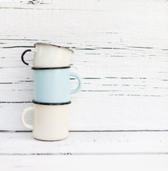 Enameled mugs in retro style on an old wooden background.