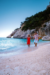 Wall Mural - young couple on vacation Sardinia, men and woman walking on the beach of Cala Goloritze during sunset hours