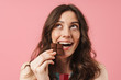 © Drobot Dean - Happy young cute woman posing isolated over pink wall background holding chocolate sweeties.