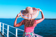 Cruise ship vacation woman enjoying travel vacation at sea. Free carefree happy girl looking at ocean and holding sunhat.