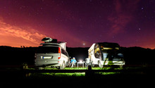 Campervans Are Parked On A Beach At Night Under Stars.