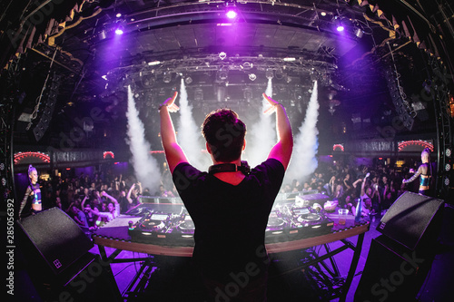 Cuadros en Lienzo DJ in nightclub with hands up and cryo canons, shot from behind