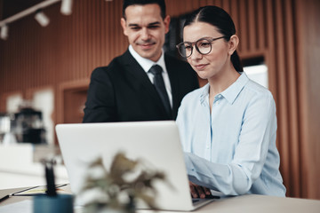 Smiling businesspeople using a laptop at an office table