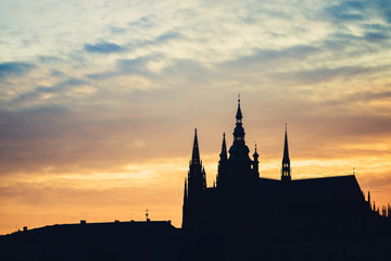 Silhouette at sunset of St. Vitus cathedral against the setting Sun from Prague, Czech Republic