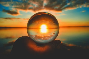 Wall Mural - creative crystal lens ball photography of the sunset with clouds blurred in the background