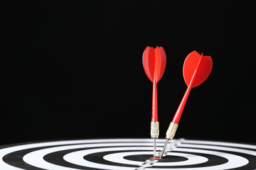 Dartboard with darts on black background