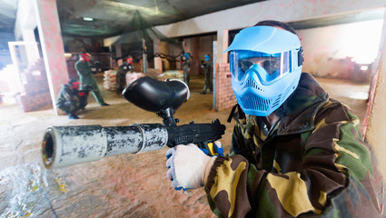 Wall Mural - Portrait of blue team player who is aiming in opponents on paintball field.