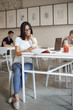 © Liubov Levytska - Vertical shot busy young woman in glasses sit alone cafe surrounded with working material notebook and laptop, using smartphone, scrolling social media feed during break from studying