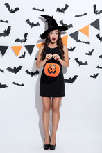 Young Woman In Halloween Costume With Pumpkin Bucket On White Background
