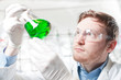 © Westend61 - Germany, Young scientist checking green liquid in Erlenmeyer flask