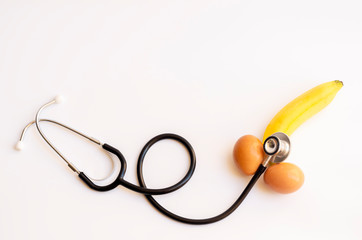 banana and two eggs representing men's penis with stethoscope on white background,take care your health take care your sex, Sexual dysfunction concept.