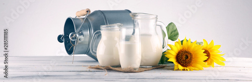 Fotomural A jug of milk and glass of milk on a wooden table and flower