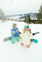 Two Young Bright Girls With Snowboards Stopped And Throw Snow