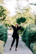 © Alexandra Coelho/ADDICTIVE STOCK - Trendy young woman in black suit walking along paved path and enjoying summer day in Lisbon