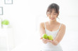 © NT_studio - Beautiful portrait young asian woman holding and eating green apple fruit in the bedroom at home, lifestyle of nutrition girl healthy and care weight loss, health and wellness concept.