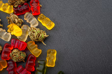 Cannabis Edibles, Medical Marijuana, CBD Infused Gummies And Edible Pot Concept Theme With Close Up On Colorful Gummy Bears And Weed Buds On Dark Background With Copy Space