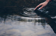 Girl touches the surface of the water on the lake with her fingers