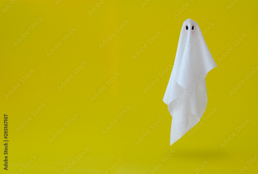White ghost sheet costume flying in the air with yellow background. Minimal Halloween scary concept. - obrazy, fototapety, plakaty 