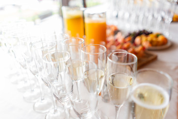 Wall Mural - reception. Table top full of glasses of sparkling white wine with canapes and antipasti in the background. champagne bubbles