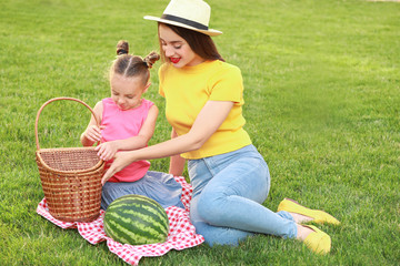 Poster - Cute little girl and her mother eating sweet watermelon in park