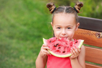 Wall Mural - Cute little girl eating sweet watermelon in park