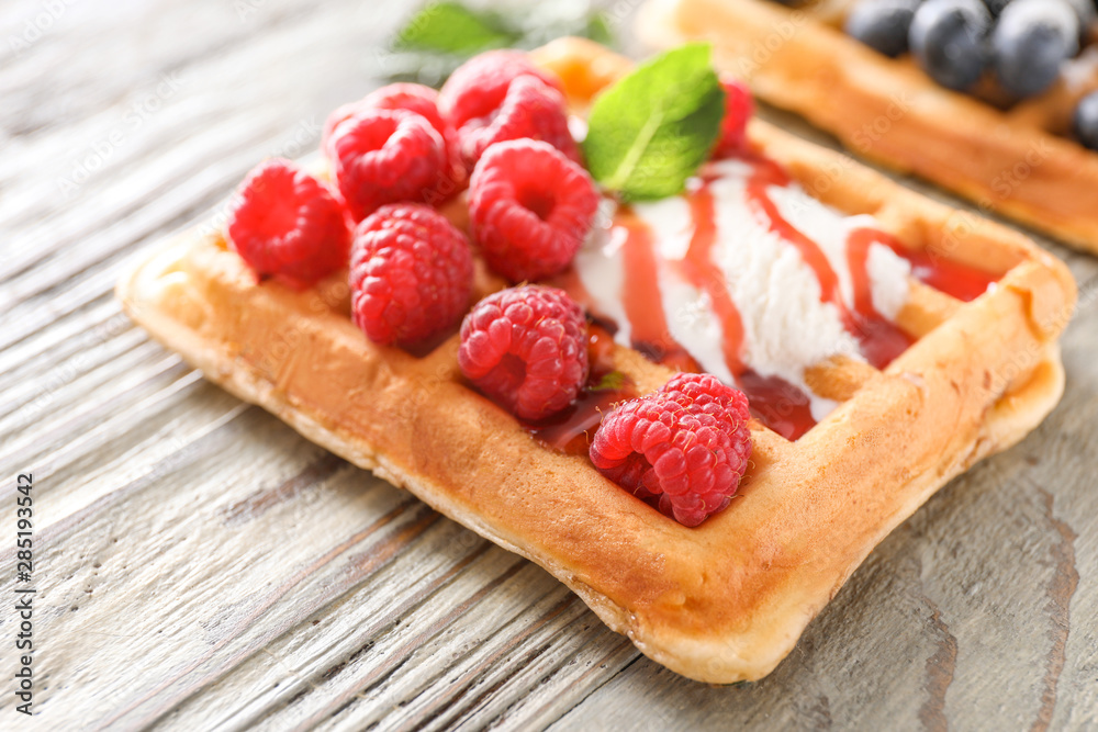 Sweet waffle with ice cream and raspberry on wooden table