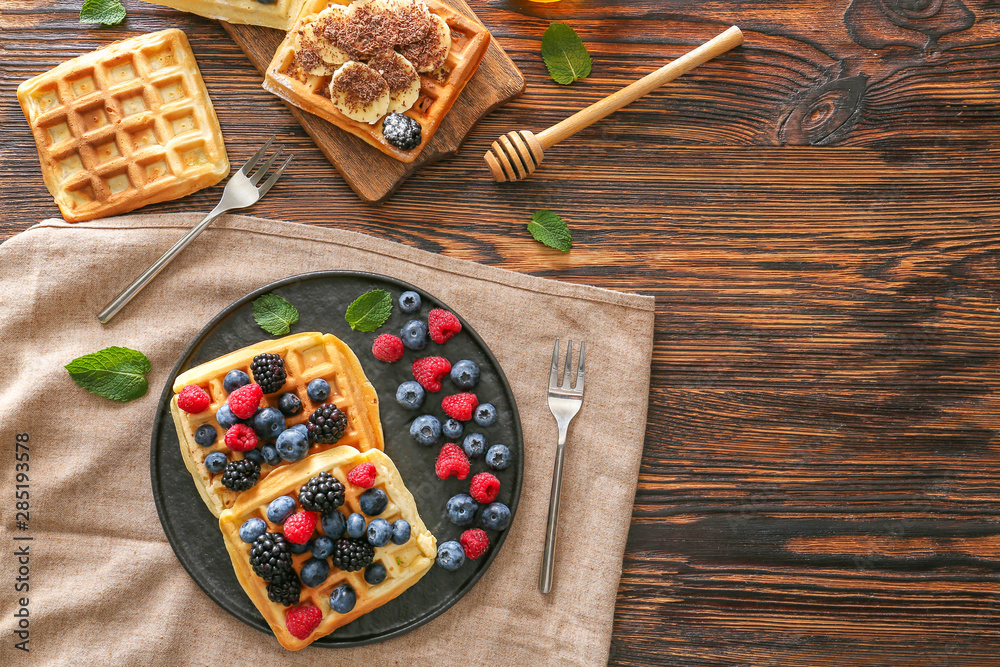 Sweet waffles with berries on wooden table