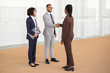 © Mangostar - Happy business partners greeting each other in office hallway. Multiethnic business man and women standing and shaking hands. Partnership concept