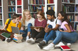 © Prostock-studio - Group of diverse students sitting on floor at library