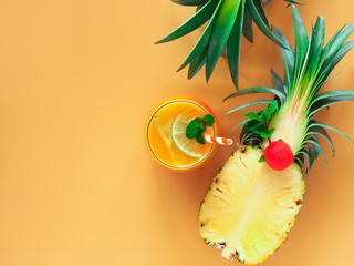 Wall Mural - Pineapple juice topping with lemon sliced and fresh mint on orange color background with copy space for summer party drinks concept.