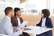 © Mangostar - Business colleagues discussing documents in outdoor cafe. Business man and women sitting at table outdoors and talking, man holding papers. Consulting concept